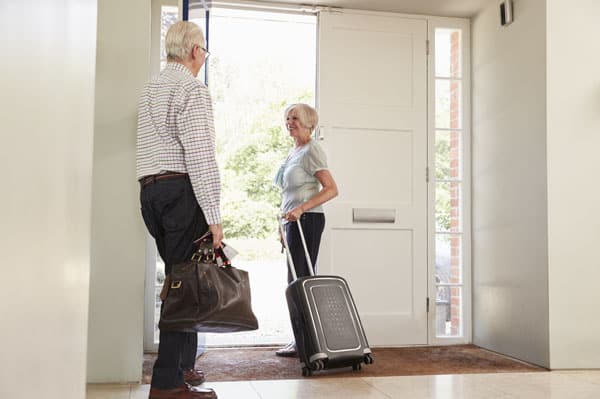 Seniorenpaar mit Koffern verlassen Wohnung